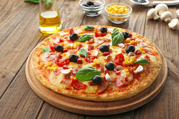 Plate with tasty pizza and its ingredients on wooden table