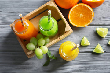 Bottles of delicious juice with ingredients on wooden background