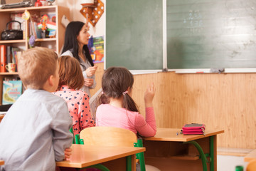 Teacher helping pupil at blackboard