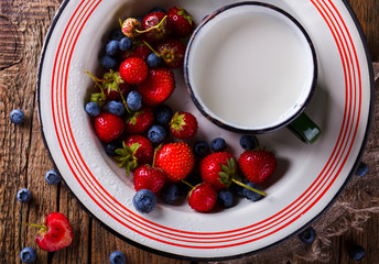 Fresh Strawberries and Blueberries  in the Iron bowl with a Cup of Milk on Vintage Wooden Background.Food or Healthy diet concept.Copy space for Text. selective focus.