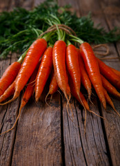 Bunch of fresh carrots with green leaves over wooden background. Vegetable.Food or Healthy diet concept.Vegetarian.Copy space for Text. selective focus.