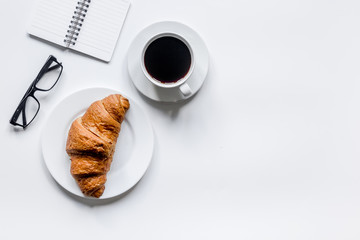 Businessman morning with notebook, cup of coffee and croissant on wooden table background top view...