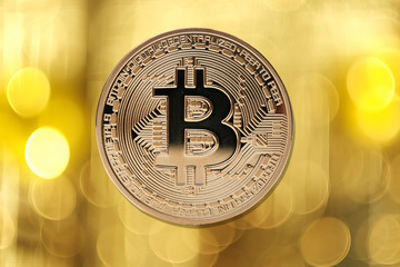 Golden bitcoin isolated on blurred light background