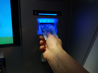 Hand inserting ATM card into bank machine to withdraw money
