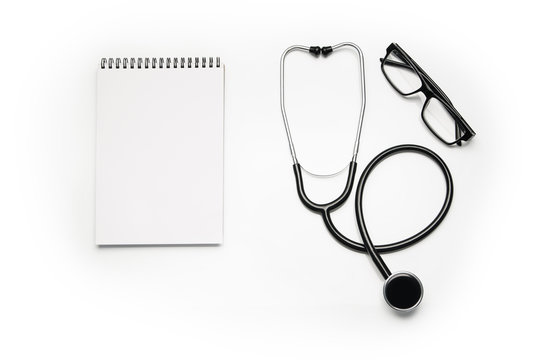 Stethoscope and prescription notepad isolated on white background. Sterile doctors office desk. Medical accessories on a white table background with copy space around products. Photo taken from above.