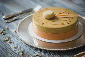 Freshly baked yellow pudding cake with almond dacquoise, raspberry confit, crispy layer with caramelized hazelnuts and raspberry powder, mousse based on bitter chocolate served on wooden table