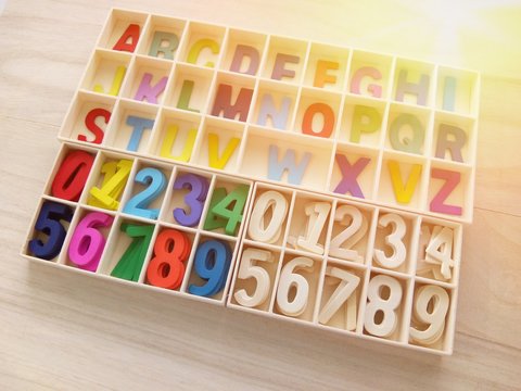 Colorful of alphabet and number in the box on a wooden background. underexposed
