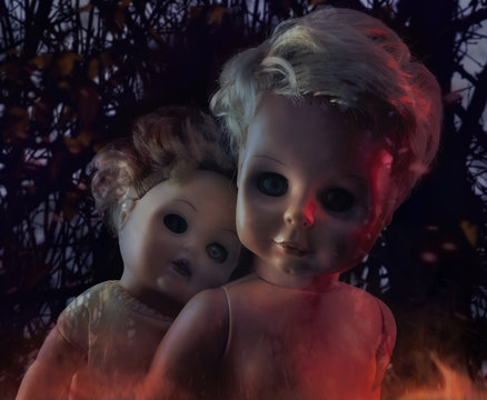 Horror dolls photo. Two burning creepy ghost dolls on mystic nature background photo.