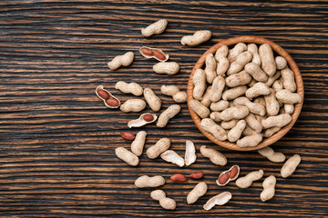 Peanuts on textured wooden background, top view.