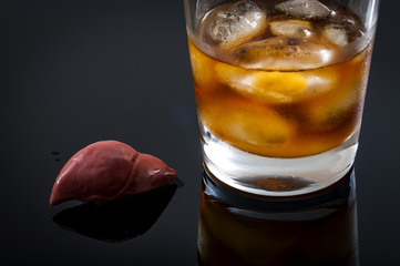 Alcoholic liver damage and cirrhosis concept with a liver next to a glass of alcohol. Cirrhosis is most commonly caused by alcoholism, hepatitis B or C or non-alcoholic fatty liver disease