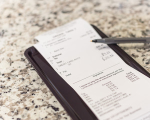 Soft focus, shallow DOF a receipt with hand written total amount and tipping from Vietnamese...