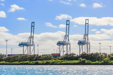 Fototapeta premium Port cargo crane and container over blue sky background, ready for shipment