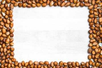 Peanut frame background. White wooden board or table surrounded with nut border in the shape of a rectangle. Groundnut backdrop and template with copy space.