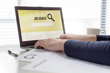 Man trying to find work with online job search engine on laptop. Jobseeker in home office. CV and...