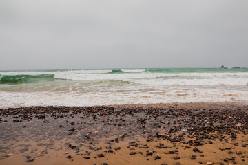 Coast, waves and beach with yellow sand and pebbles