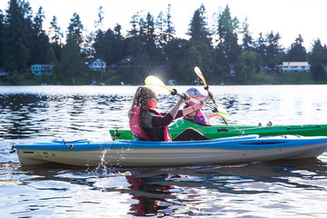 two kids racing on a lake in kayaks