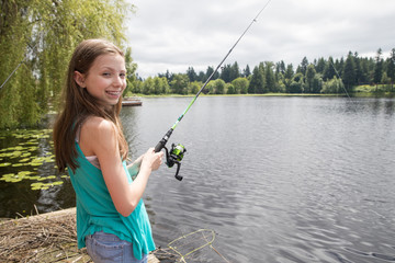 Cute young girl with braces fishing on a lake