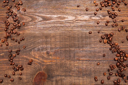 Roasted coffee beans frame on wooden background. Closeup of seeds on dark brown table. Top view.