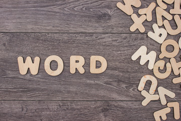 Word word made with block wooden letters next to a pile of other letters over the wooden board