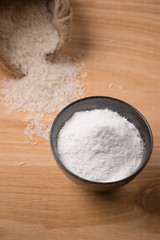 Jasmine white rice in sack and rice flour on wooden table.