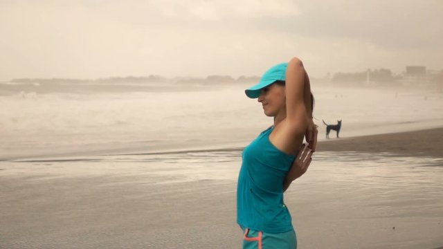 Sporty woman exercising, stretching arms on beach, super slow motion 240fps
