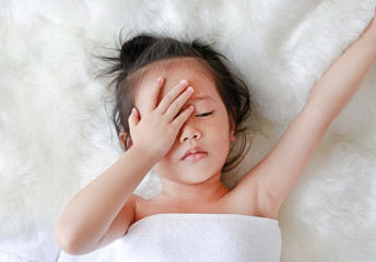 child girl in towel lying on the bed at the morning.