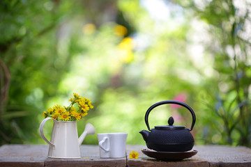 Obraz na płótnie Canvas Black teapot and cup with flower at outdoor