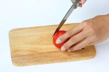 Tomato slices on wood block with knife against white background.