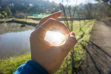 Woman hand in ok sign with light reflected from the sun in O sign. 