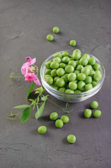 .Healthy food. Fresh green peas in glass bowl with pink flowers of sweet pea