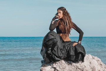 Attractive young woman in black dress on the beach