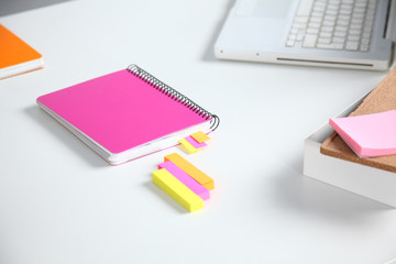 Closeup of white desktop with notepads, pen, coffee cup and other items. Selective focus.