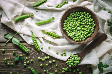 Fototapeta na wymiar Delicious ripe green peas lying on a wooden table.