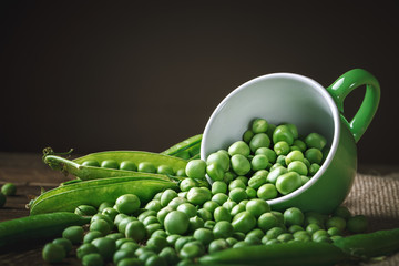 Delicious ripe green peas lying on a wooden table.