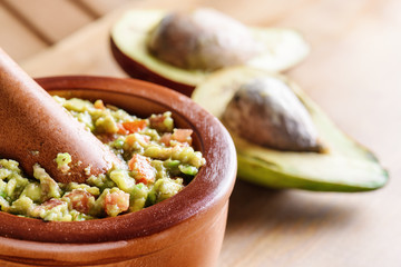 Closeup view of fresh homemade Guacamole in wooden mortar