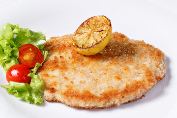 German schnitzel with lemons and limes, tomatoes and lamb's lettuce salad
