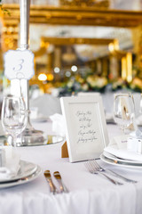 Frame with lettering on white paper inside stands on the dinner table