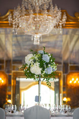 Tall bouquet of blue and white hydrangeas stands in the middle of dinner table