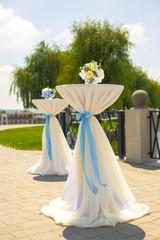 Little bouquets of blue hydrangeas stand on little tables outside