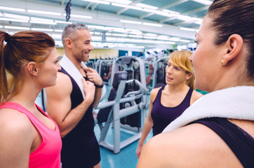 Fototapeta premium Group of women friends talking with personal trainer of a fitness center. Selective focus over girl back on right.