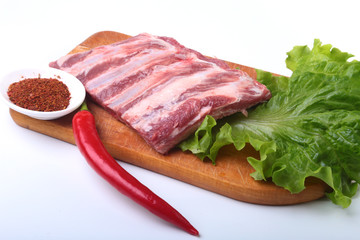 Raw pork ribs with herbs and spices on wooden board. Ready for cooking.