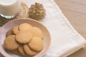 Homemade bakery:Thin biscuits or cookies baked from multi grains so delicious, crisp and crack snack. Biscuits cookies on rustic wood table serve with fresh milk. Golden brown cookies on lovely plate.