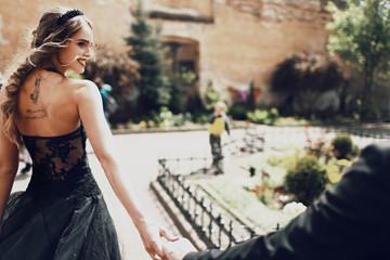 Bearded man holds woman's hand walking with her on the backyard