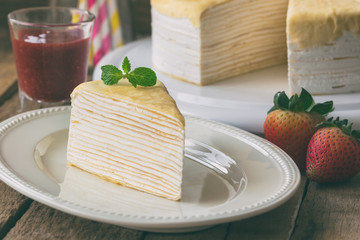 Homemade crepe cake and strawberry sauce decorate by mint. Triangle slice piece of crepe cake or mille crepe. French dessert: crepe cake for tea time,cafe or coffee break and birthday party.