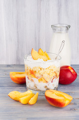 Healthy breakfast with corn flakes, ripe slice peach and milk bottle on white wood board.