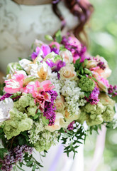 Bride holds rich wedding bouquet made of white and violet flowers