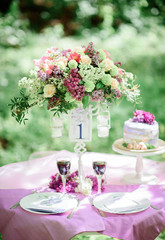 Table number one with bouquet of violet flowers and little cake on it