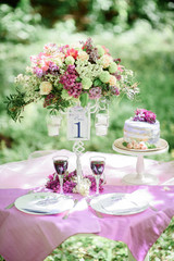 Table number one with bouquet of violet flowers and little cake on it