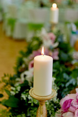 Obraz na płótnie Canvas Candle in a Golden candlestick on the table of the newlyweds. Wedding floristry