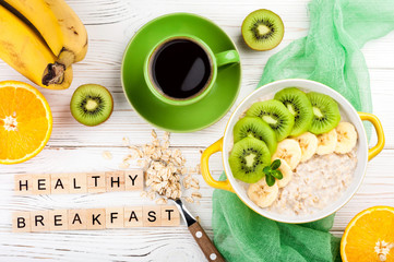 Breakfast with oatmeal porridge, coffee cup and fruits. Oatmeal with kiwi and banana. Healthy breakfast and eating  concept. Top view